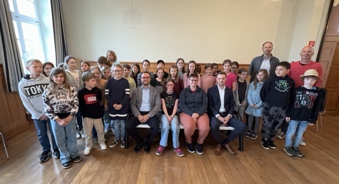 Gruppenfoto mit Erwachsenen und Kindern in einem Saal.